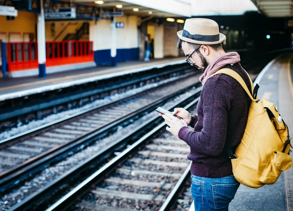 Popotnik na peronu po pristanku v tujini pregleduje telefon
